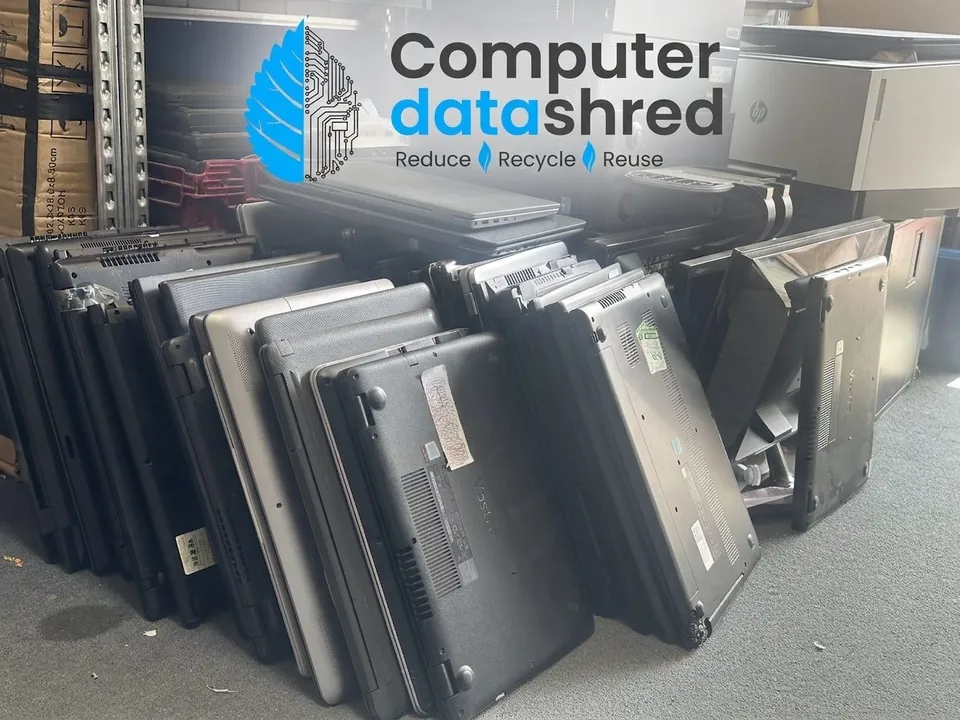 Retired laptops stacked beside Computer Data Shred collection equipment